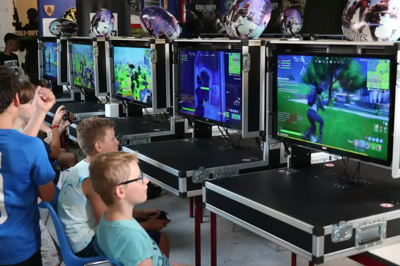 Jongeren spelen Fortnite op professionele PS5-gamestations in flightcases met Fortnite-ballonnen