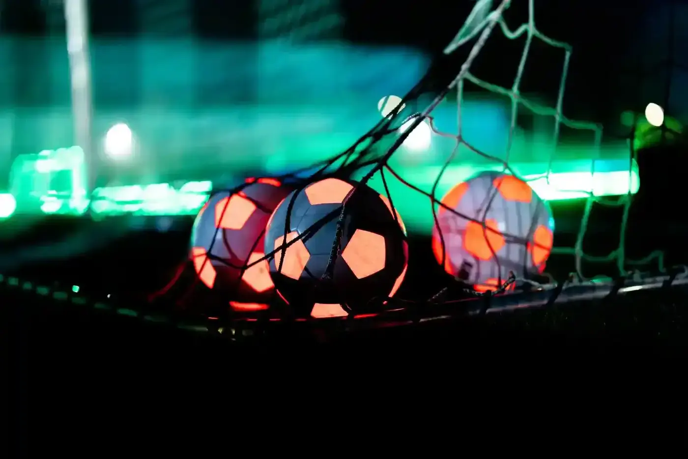 Close-up van oplichtende voetballen in een doelnet met groene en rode LED-verlichting op de achtergrond