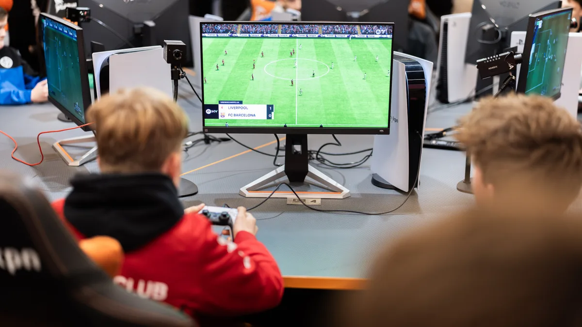 Jongeren spelen EA FC op PlayStation 5 tijdens de KNVB x WePlay United finale in de KPN E_Room