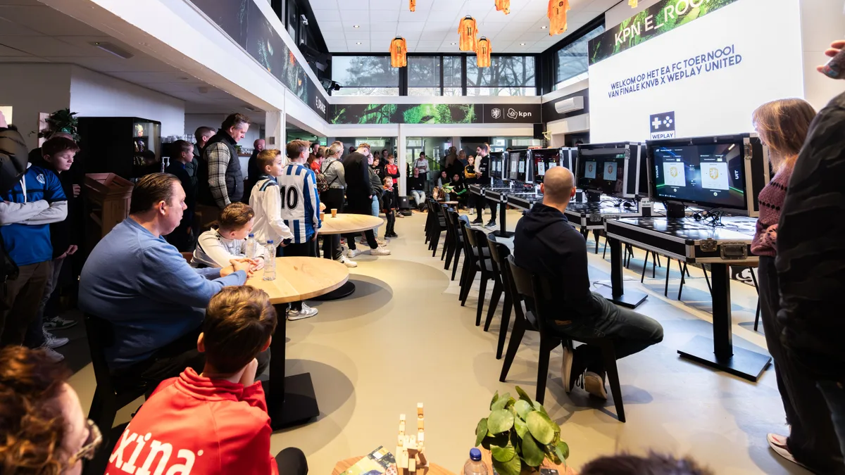 Overzicht van de KPN E_Room gevuld met deelnemers en PS5-gamestations tijdens het EA FC toernooi